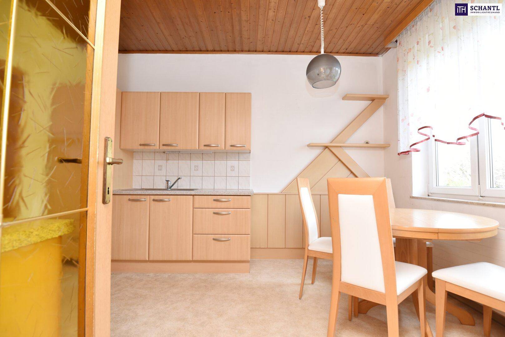 Essbereich in der Küche mit Holztisch, Stühlen und Blick auf die Küchenzeile.