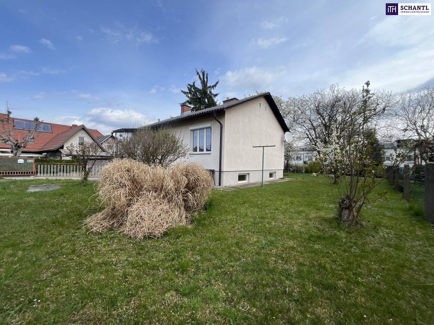 Seitenansicht des Hauses mit Rasenfläche und Heuhaufen im Garten.