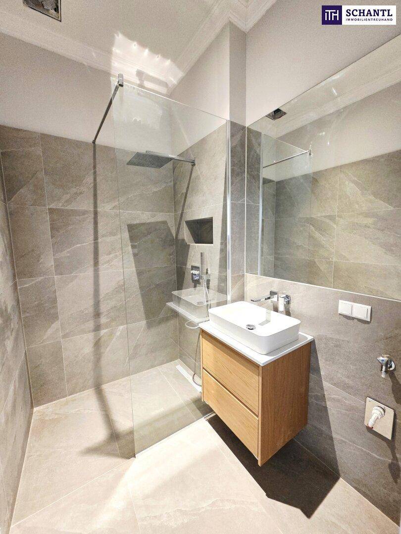 Modernes Badezimmer mit begehbarer Dusche, Einzelwaschbecken und großen Fliesen.