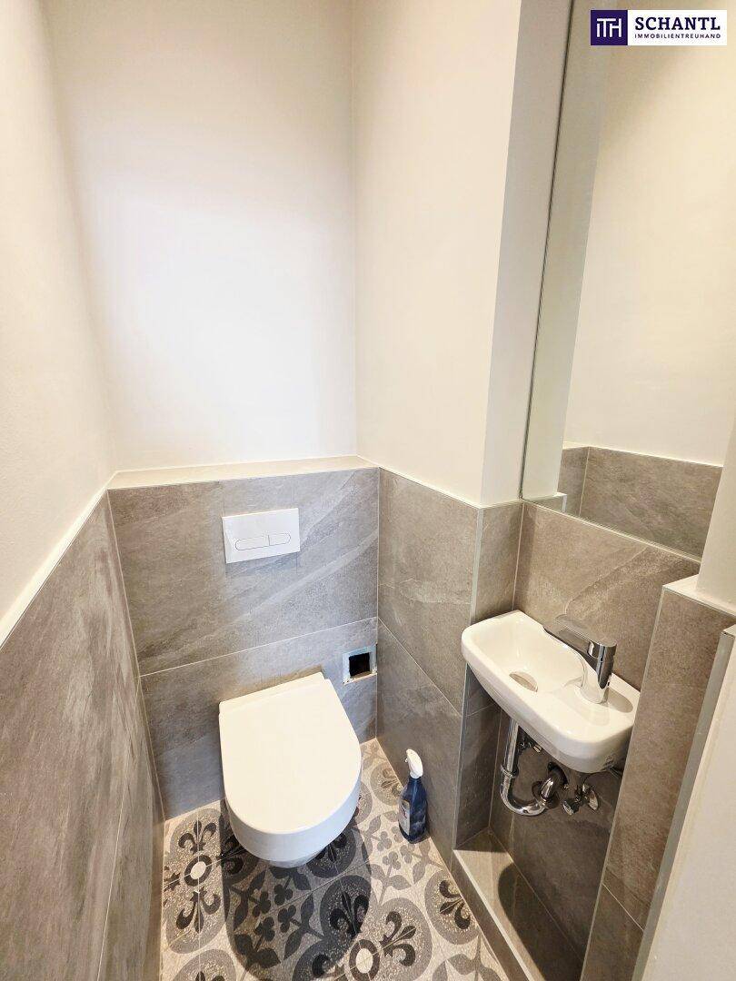 Modernes Gäste-WC mit Wand-WC, kleinem Waschbecken und dekorativen Bodenfliesen.