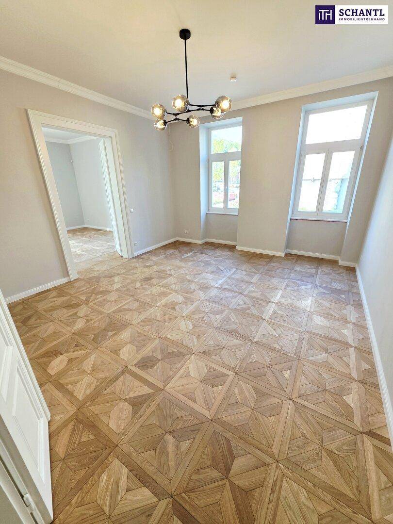 Helles Zimmer mit elegantem Parkettboden und hohen Fenstern, ideal für ein Wohnzimmer.