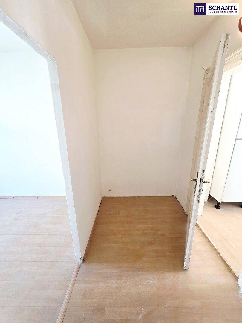 Kleiner Eingangsbereich mit Holzboden und weiß gestrichenen Wänden, der zu einem Zimmer führt.