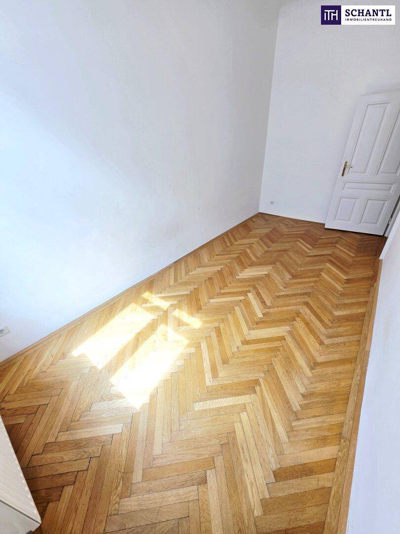 Heller Raum mit glänzendem Fischgrätparkett und viel Tageslicht, das durch die Fenster fällt.
