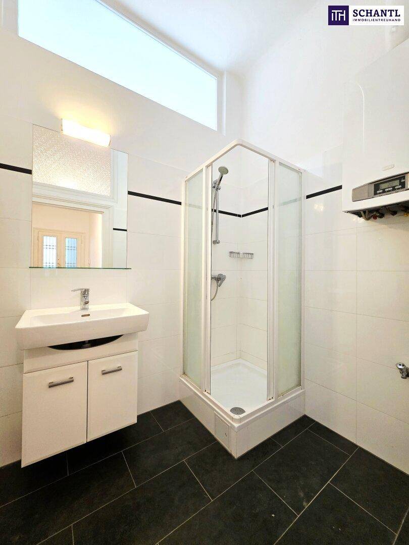 Modernes Badezimmer mit Duschkabine, Waschbecken und dunklem Fliesenboden.