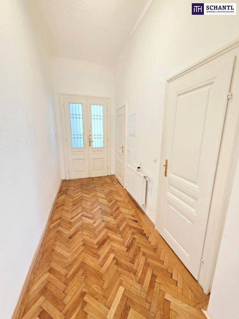 Heller Flur mit Fischgrätparkett und weißen Türen, der zu den Wohnräumen führt.