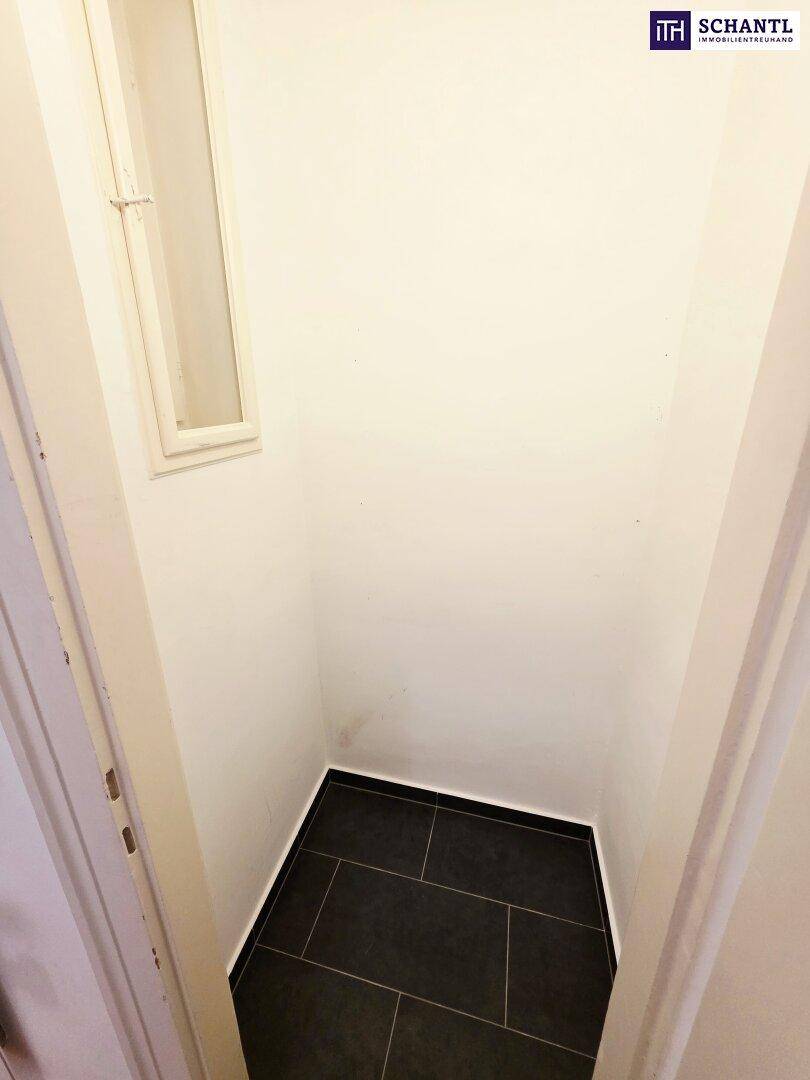 Kleiner Abstellraum mit dunklem Fliesenboden und einem Fenster für Belüftung.