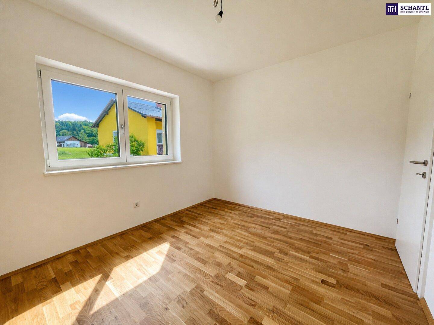 Gemütliches Schlafzimmer mit Parkettboden und Fenster, das einen Ausblick auf die Umgebung bietet.