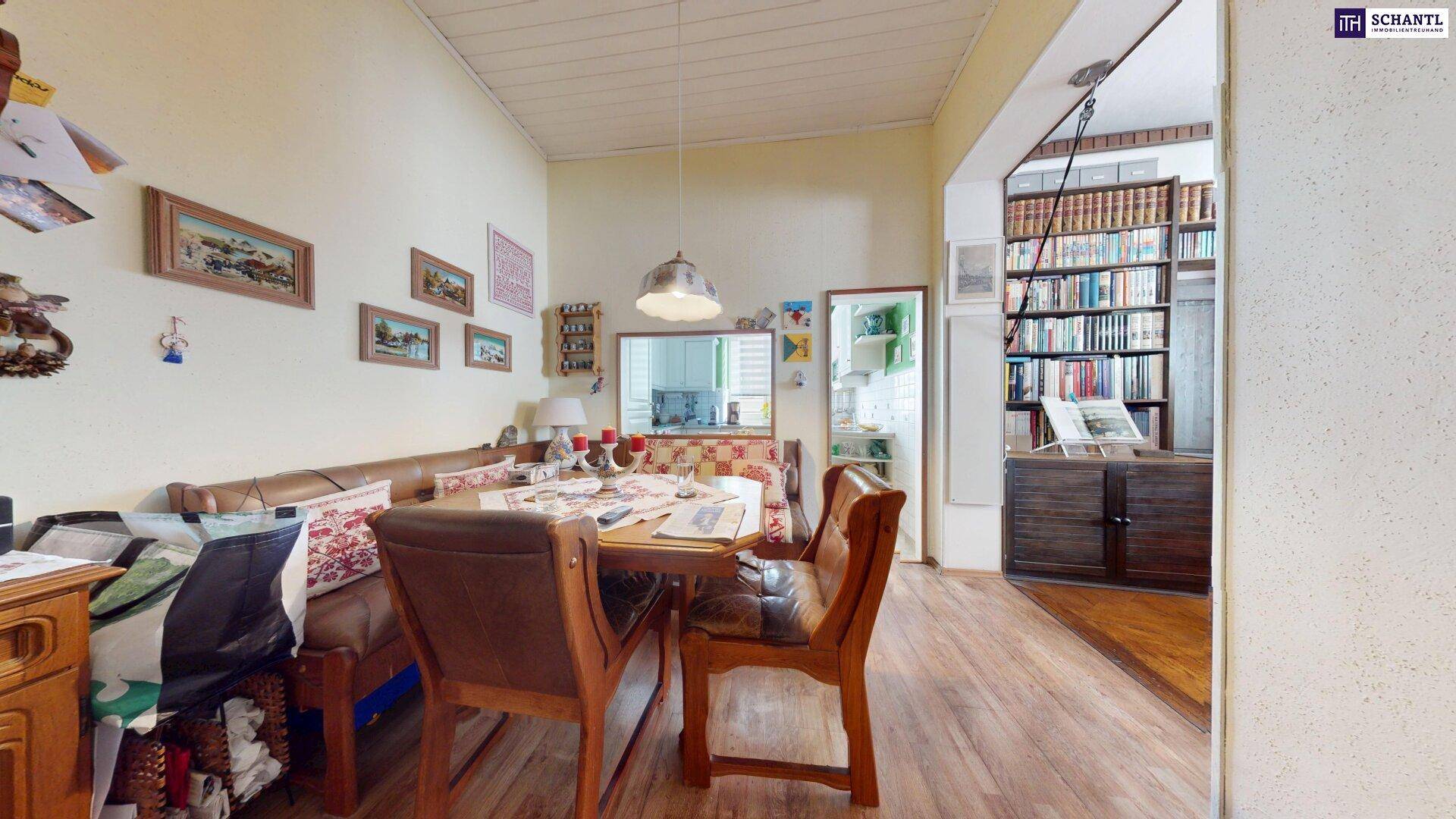 Gemütlicher Essbereich mit Holzboden, Eckbank und Blick in ein Bücherzimmer.