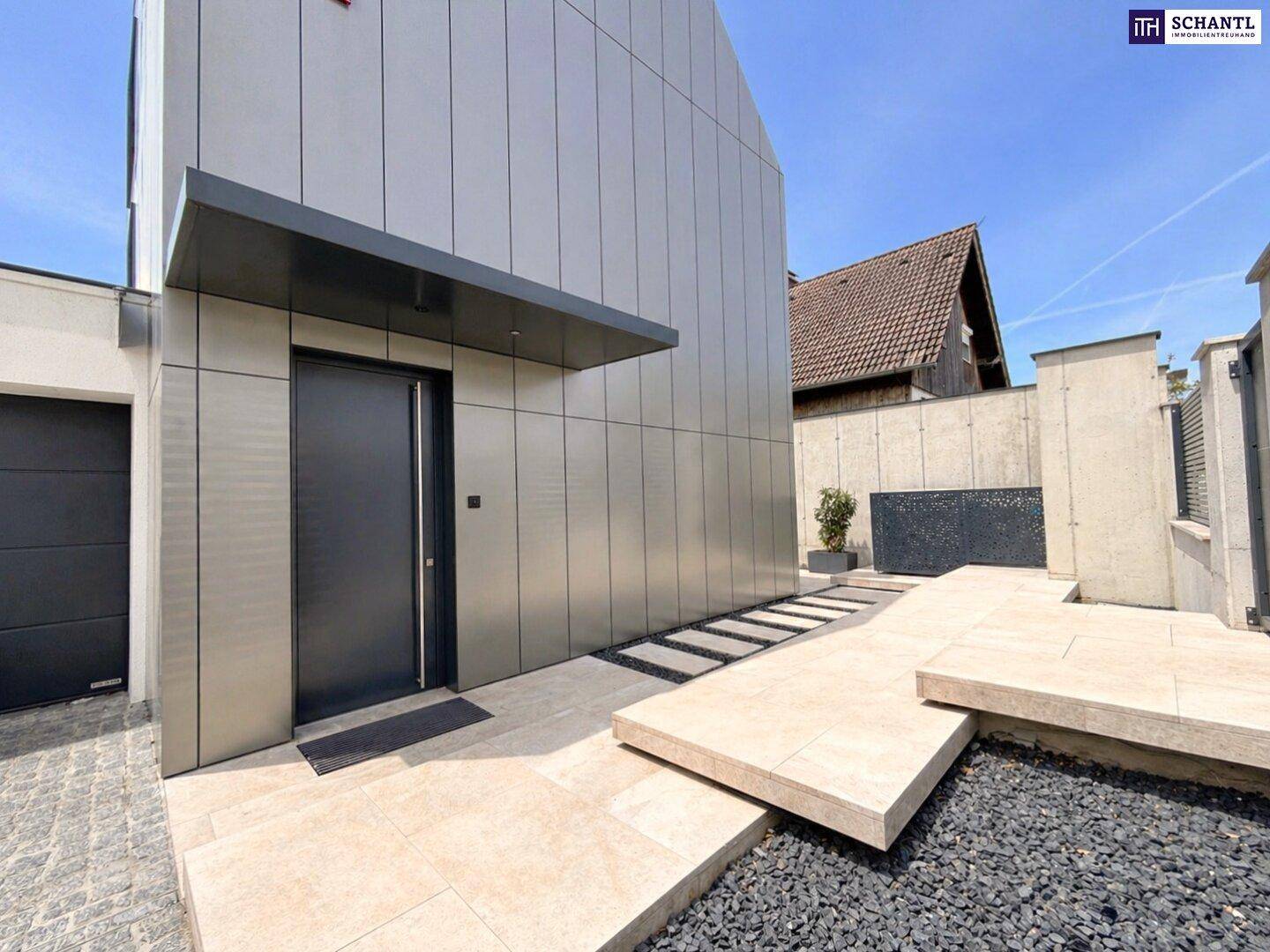 Moderner Hauseingang mit schlichter Fassade und barrierefreiem Zugang.