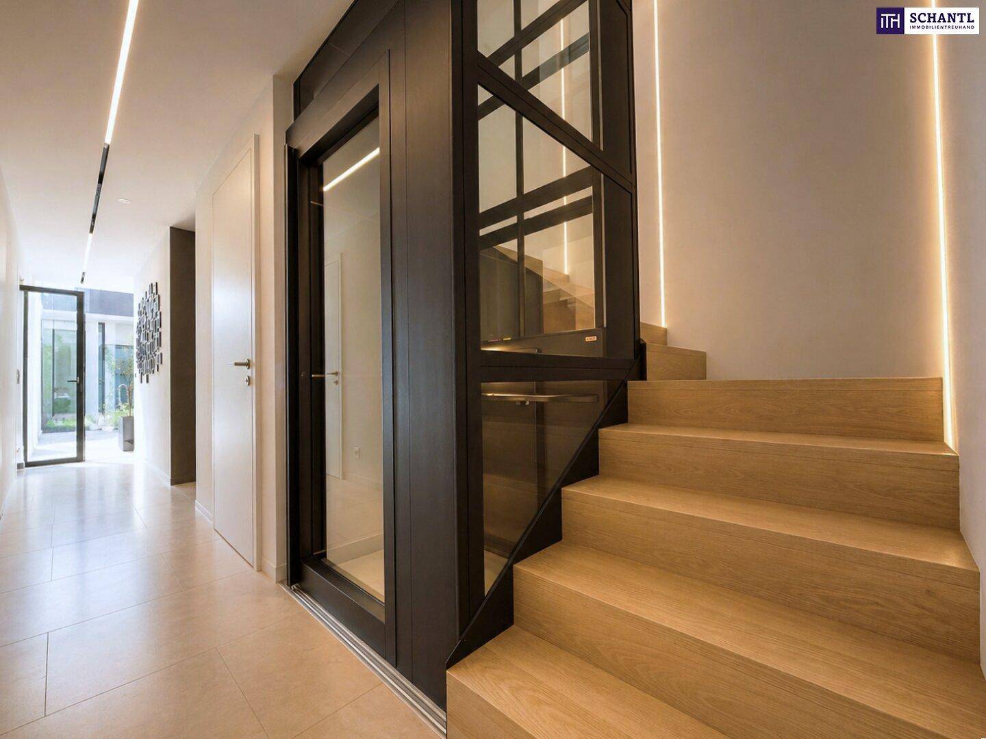 Heller Flur mit moderner Treppe und integriertem Glasaufzug für barrierefreien Zugang.