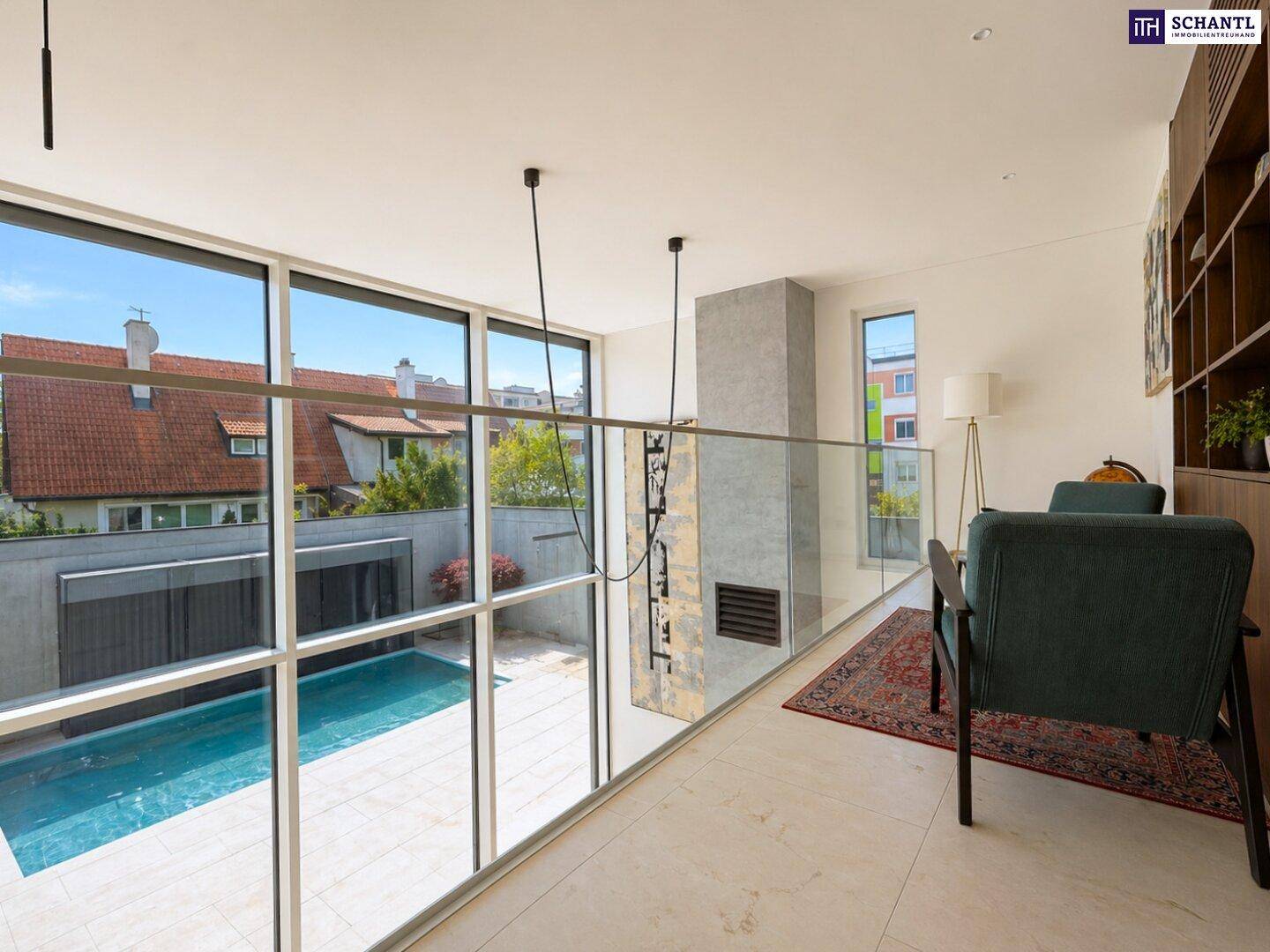 Offene Galerie im Obergeschoss mit Glasgeländer und Blick auf den Wohnbereich und Pool.