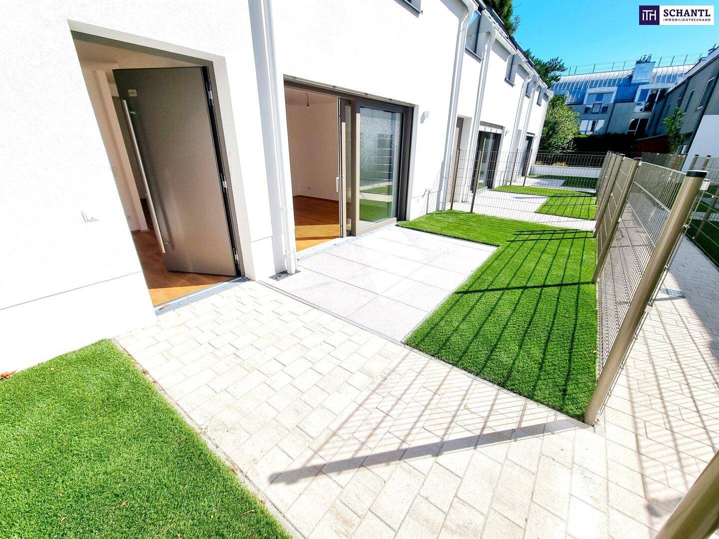 Außenbereich mit gepflasterter Terrasse und Kunstrasen, ideal für Entspannung.