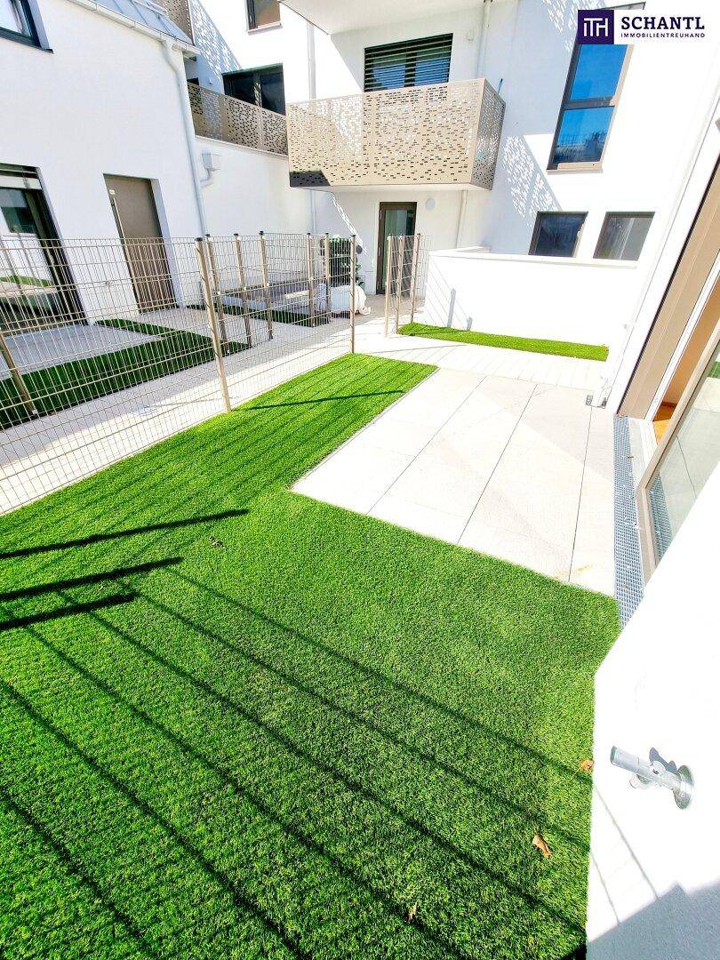 Private Terrasse mit Kunstrasen und gepflastertem Bereich in einer modernen Wohnanlage.