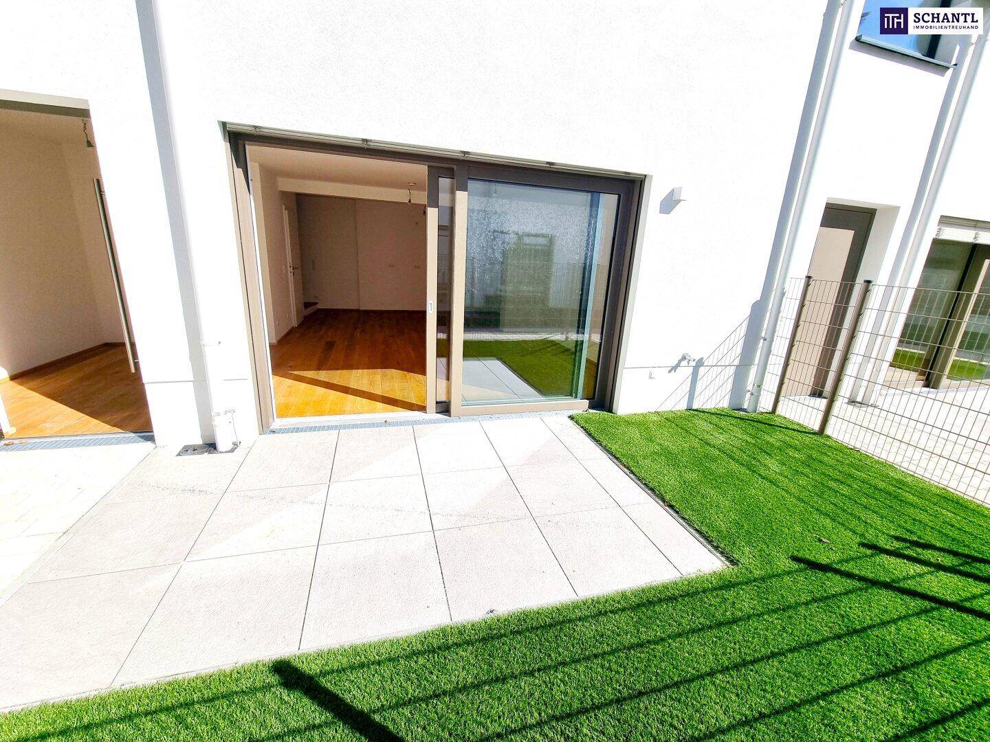 Sonniger Terrassenbereich mit Kunstrasen und Zugang zum Wohnzimmer.