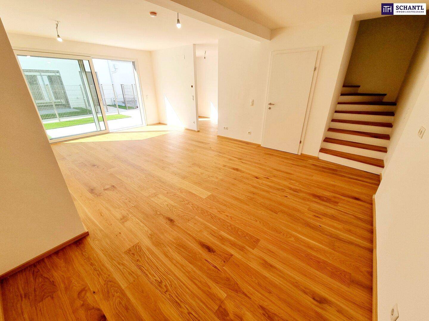 Offener Wohnbereich mit Holzparkett und Treppenzugang zu weiteren Etagen.