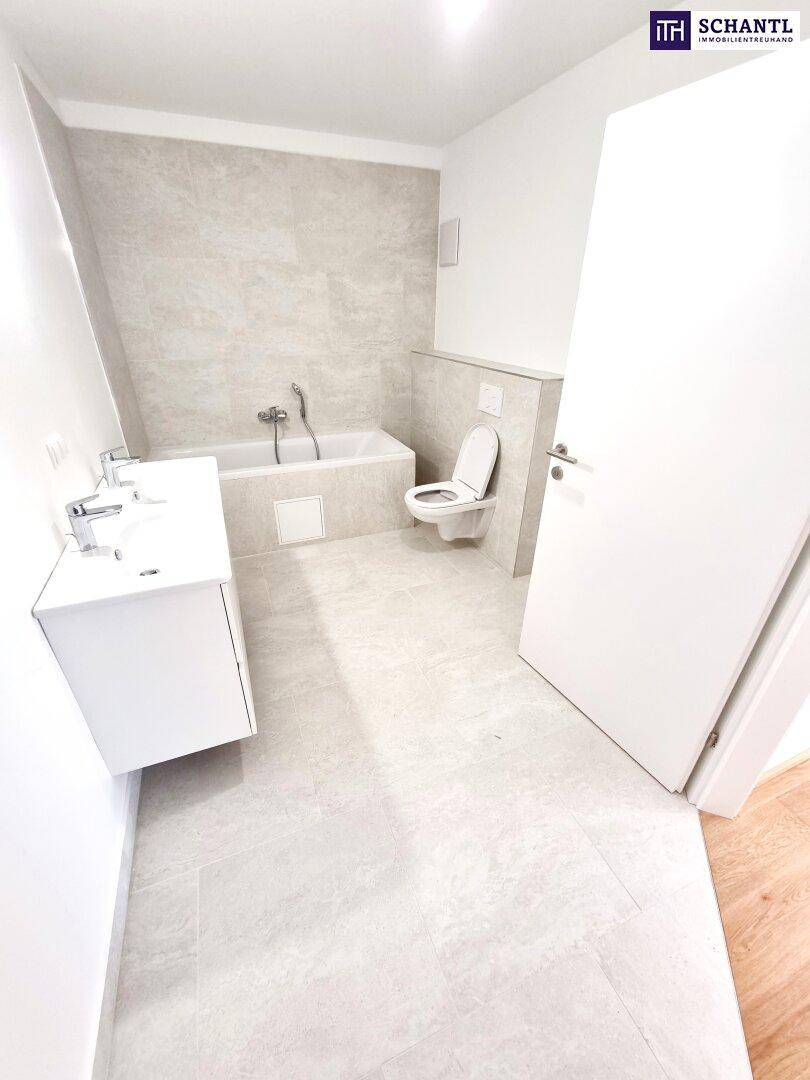 Modernes Badezimmer mit Badewanne, Toilette und Waschtisch in hellen Fliesen.
