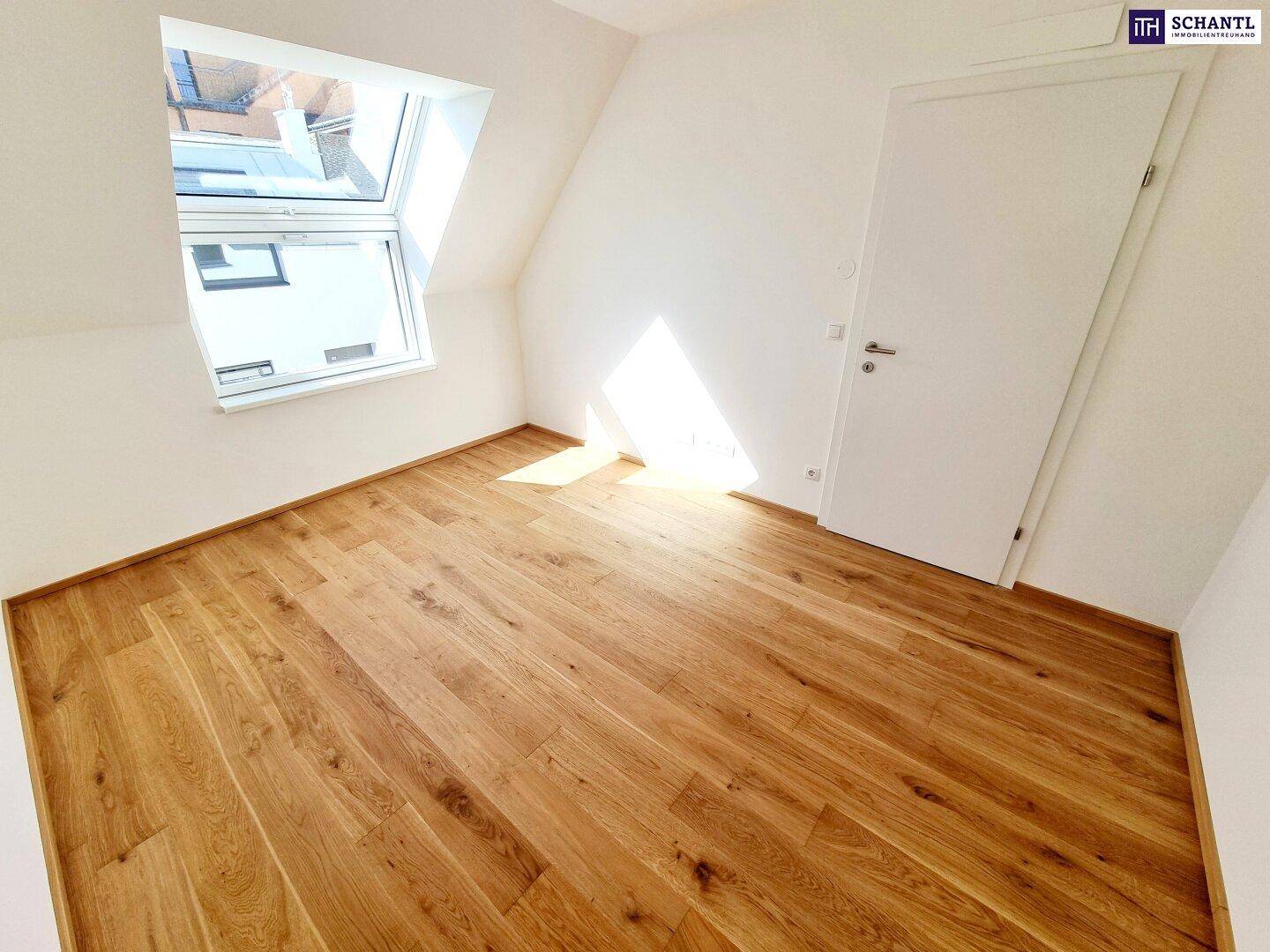 Gemütliches Schlafzimmer mit schrägen Wänden, Holzboden und viel Tageslicht.