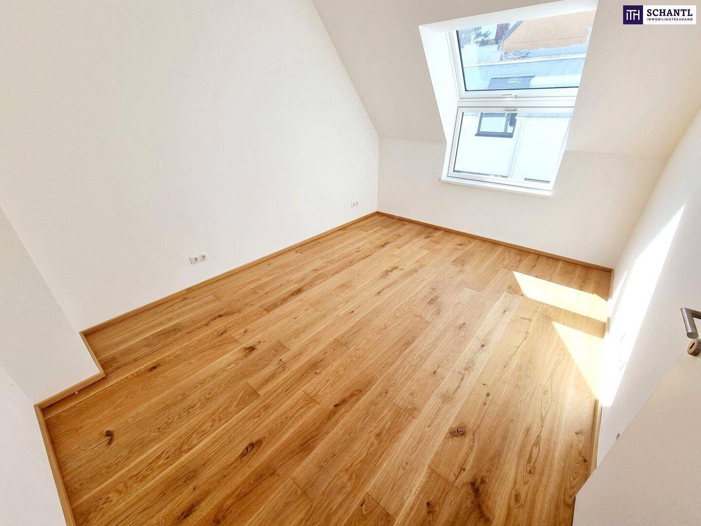 Helles Schlafzimmer im Dachgeschoss mit Holzboden und Dachfenster.