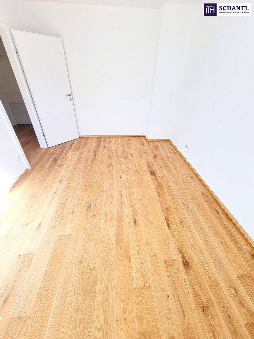 Leeres Schlafzimmer mit Holzboden und weiß gestrichenen Wänden im Dachgeschoss.