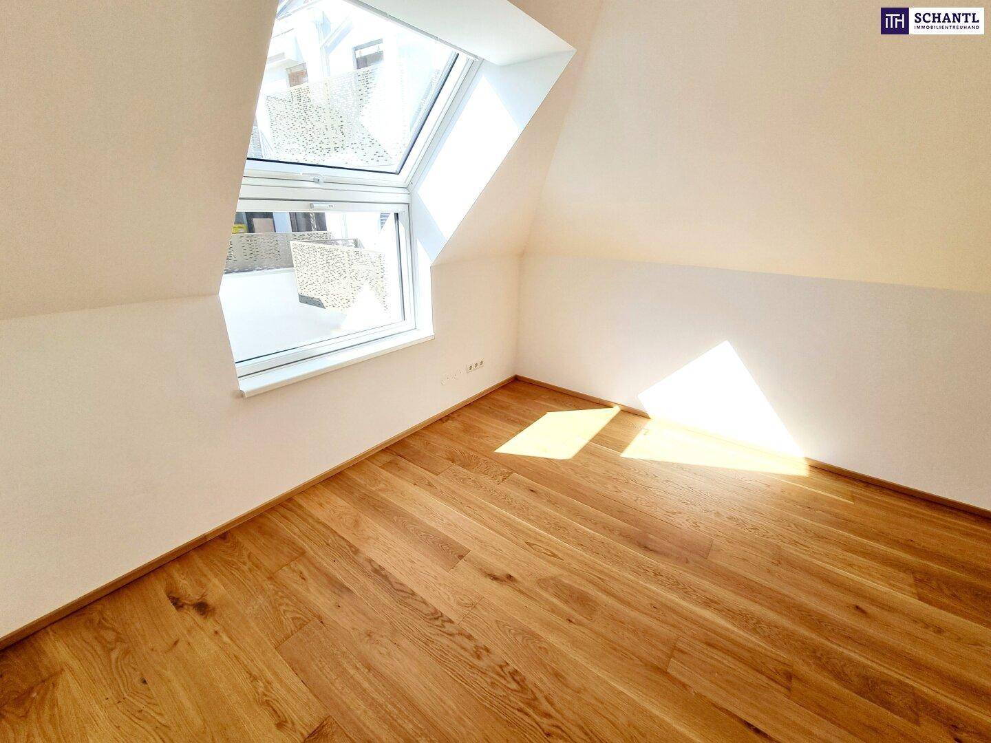 Dachgeschosszimmer mit Holzboden, weiß gestrichenen Wänden und viel Tageslicht.