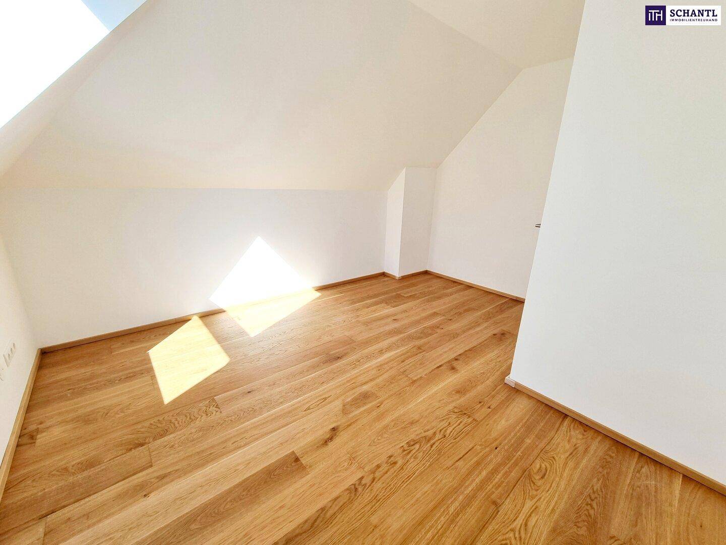 Helles Dachgeschosszimmer mit Holzboden und schrägen Wänden, ideal als Schlafzimmer.