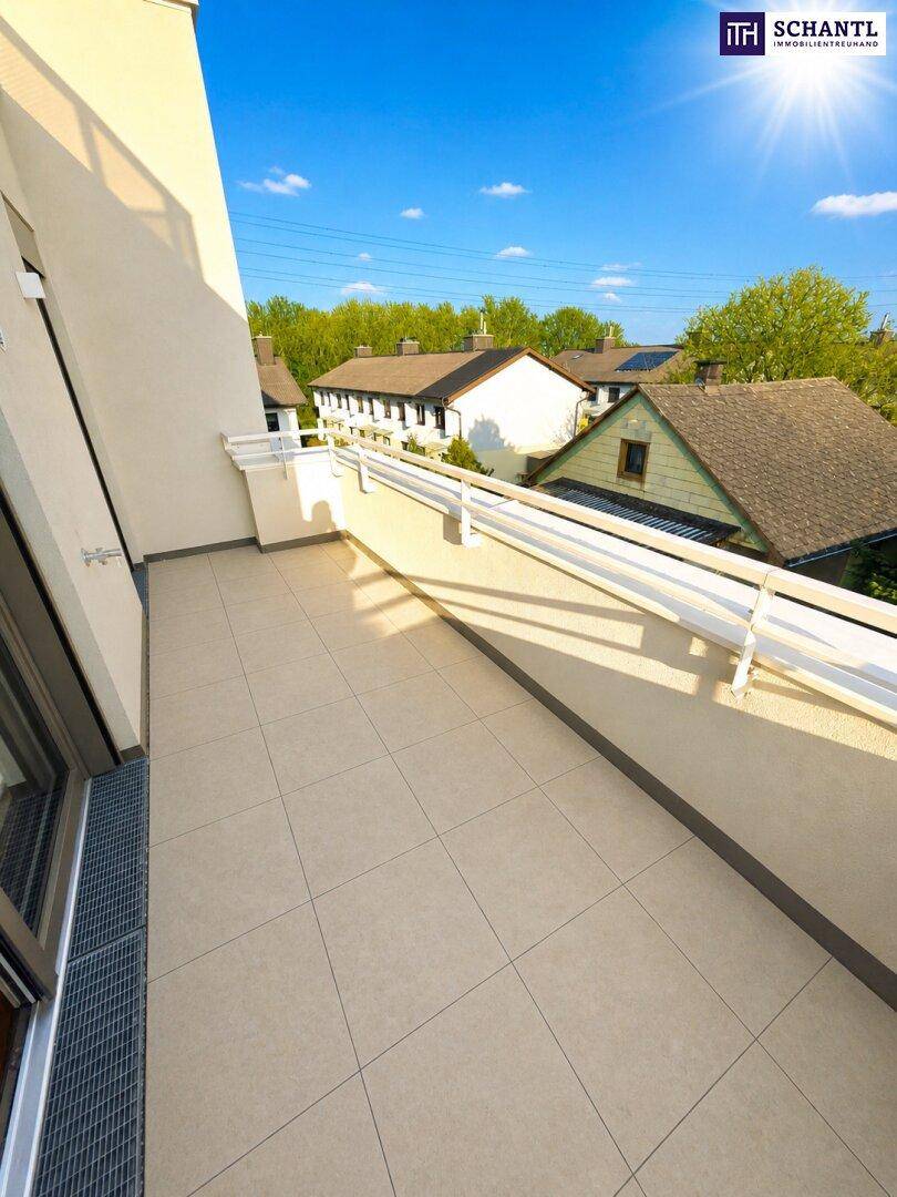 Langer Balkon mit Fliesenboden, weißem Geländer und sonnigem Ausblick auf die Umgebung.