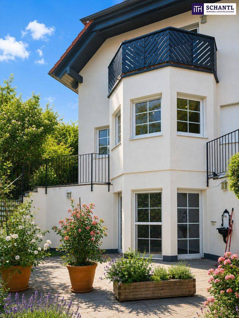 Gepflasterter Terrassenbereich am Haus mit Blumentöpfen und Zugang zu einer oberen Ebene über eine Steintreppe.
