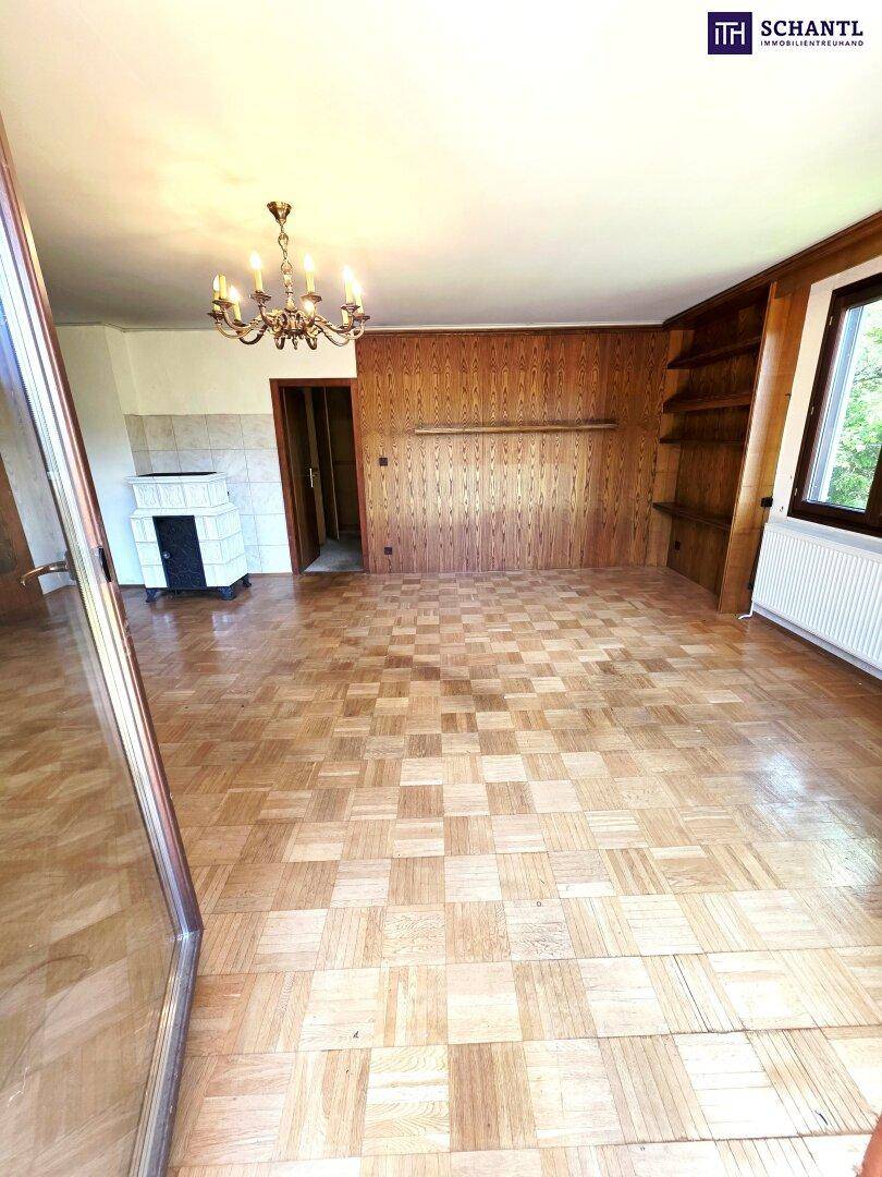 Helles Wohnzimmer mit Parkettboden, Kachelofen und traditionellen Holzwänden.