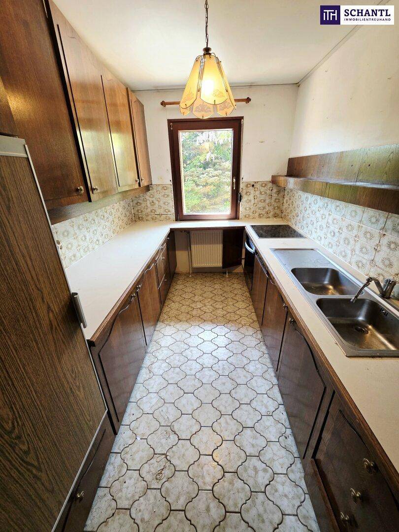 Funktionale Küche im Vintage-Stil mit Holzschränken, Doppelspüle und Fenster.