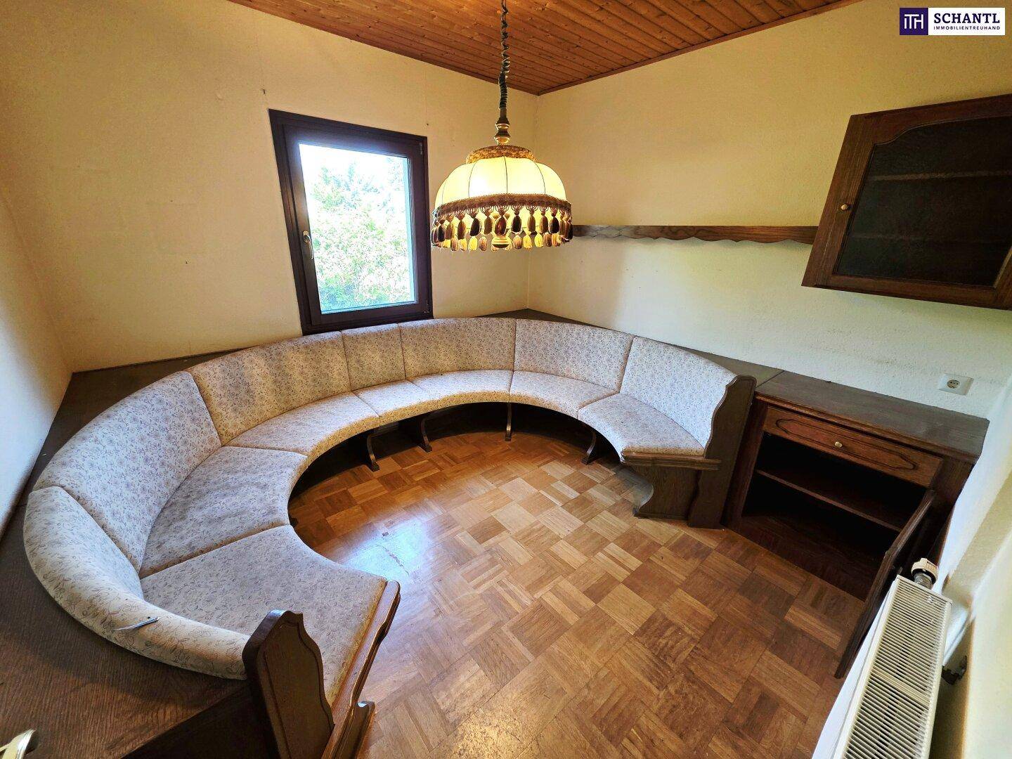 Gemütlicher Essbereich mit runder Sitzbank, Holzboden und traditioneller Deckenlampe.