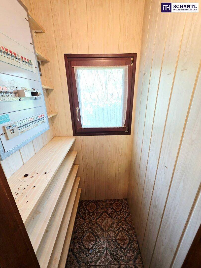 Praktischer Abstellraum mit Regalen, Fenster und Sicherungskasten.