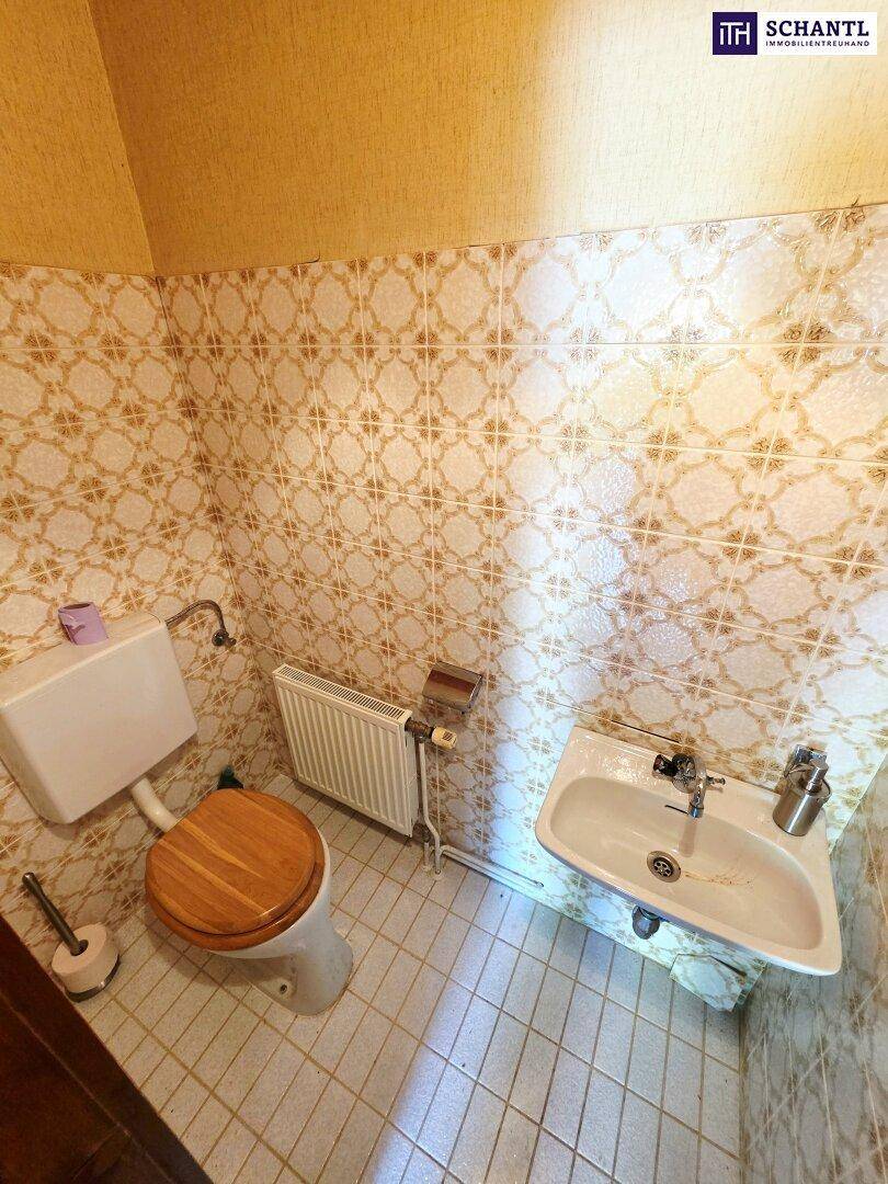 Kleines Gäste-WC mit WC, Waschbecken und traditionellen Fliesen an Wänden und Boden.