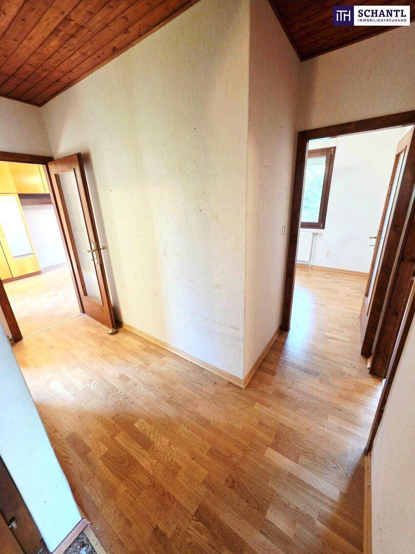Heller Flur mit Holzparkettboden und Holztäfelung an der Decke, der zu verschiedenen Räumen führt.