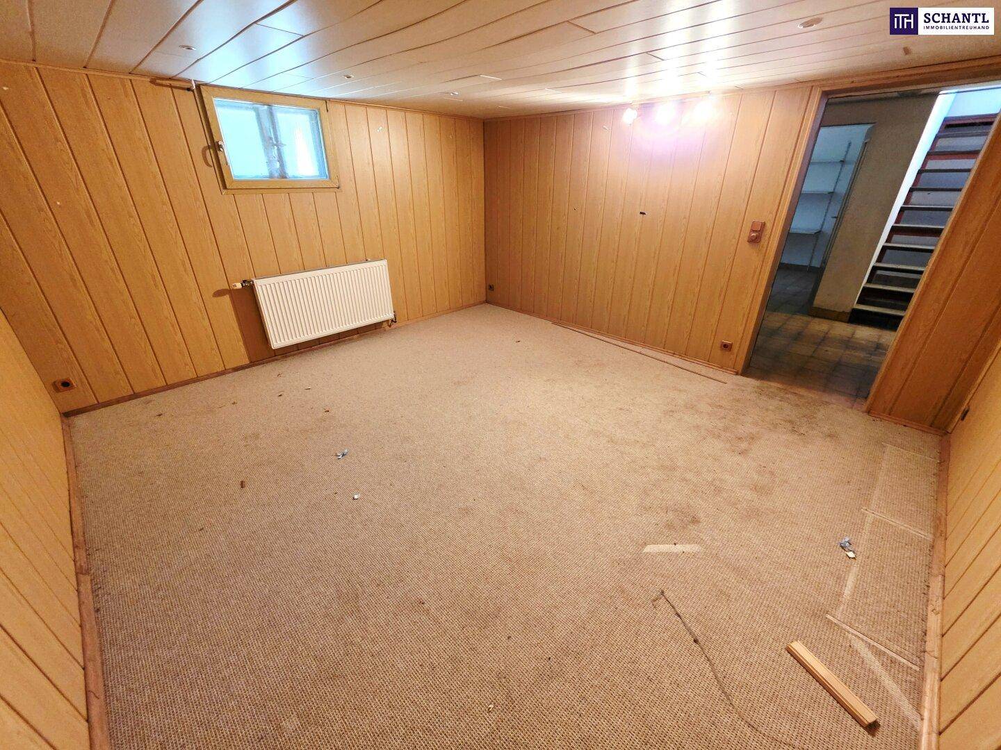 Kellerraum mit Holzvertäfelung, Teppichboden und kleinem Fenster, ideal als Hobbyraum.