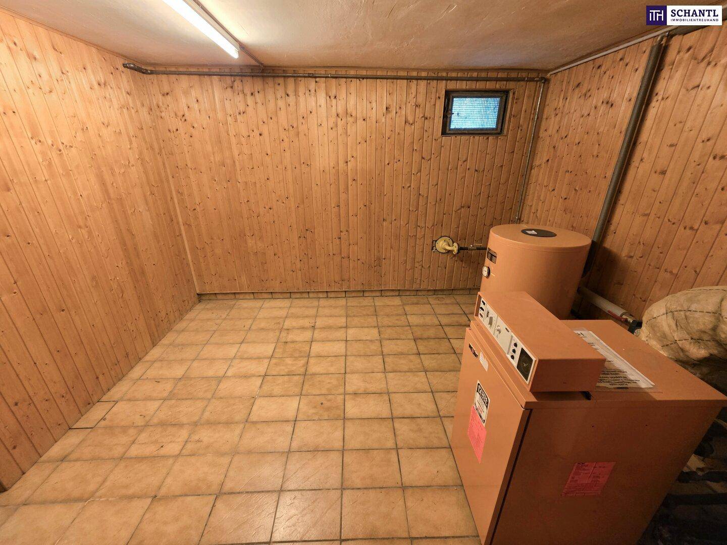 Heizungsraum im Keller mit Holzvertäfelung, Fliesenboden und Heizungsanlagen.