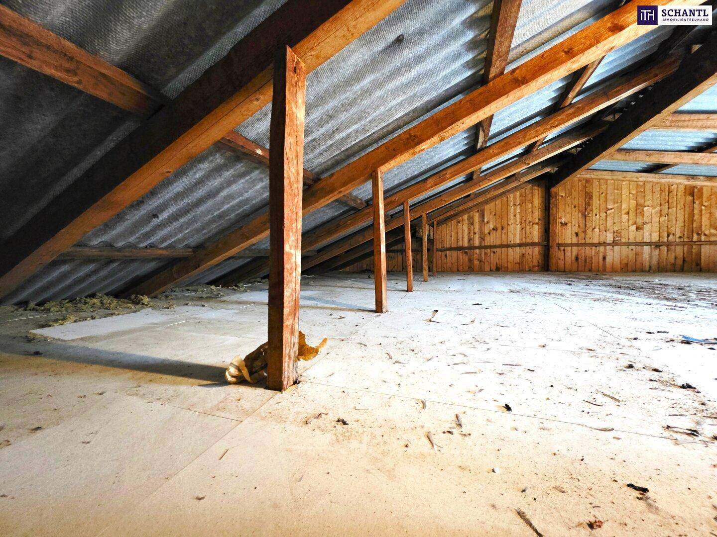 Weitere Ansicht des Dachbodens mit Holzbalken und viel ungenutztem Raum.