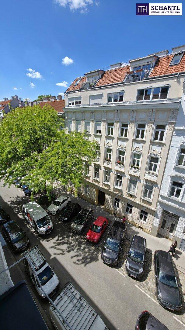 Historisches Wohngebäude mit Mansarddach und parkenden Autos auf der Straße.