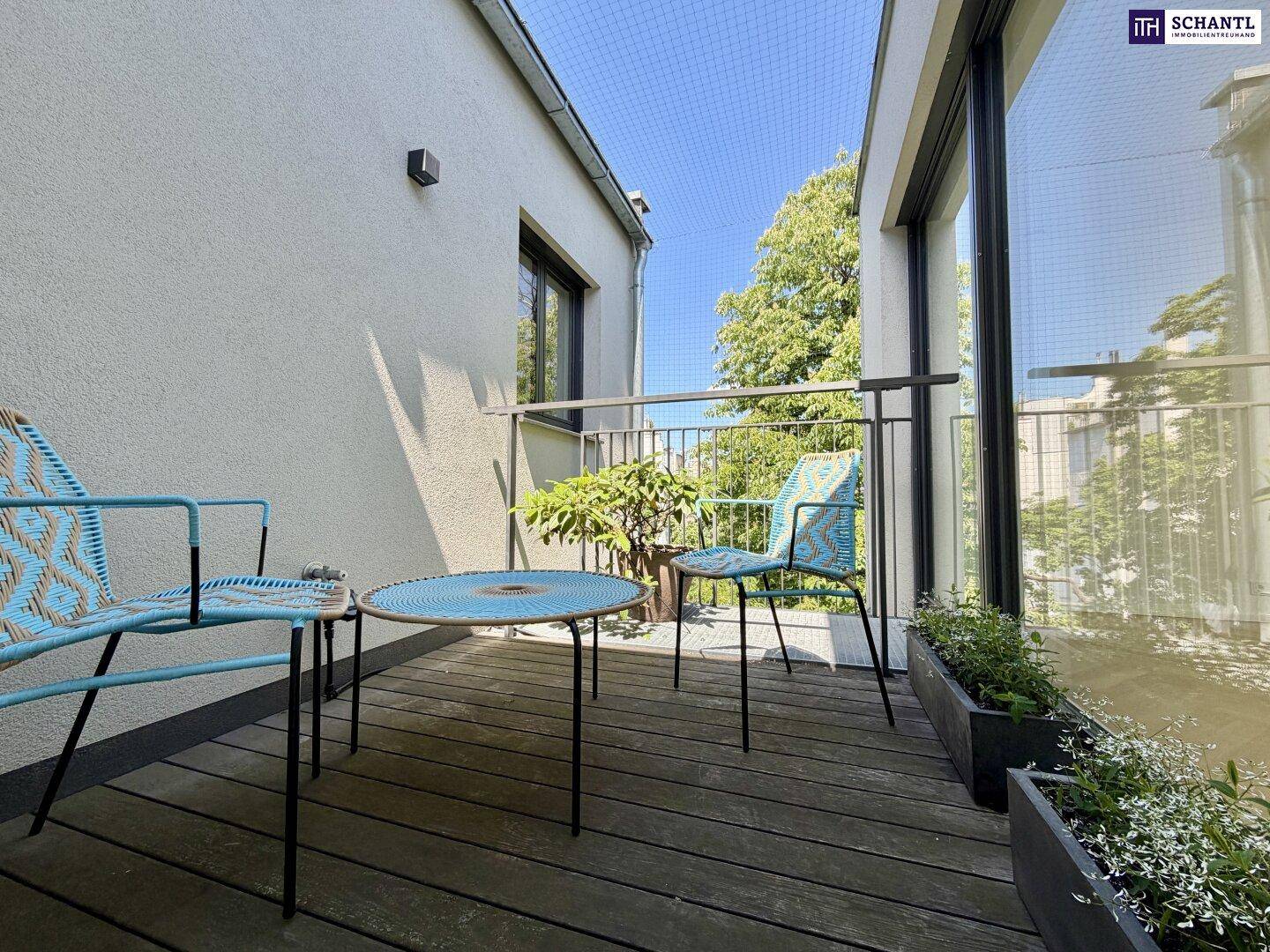 Gemütlicher Balkon mit Holzboden, Sitzgelegenheiten und Blick ins Grüne, geschützt durch ein Netz.