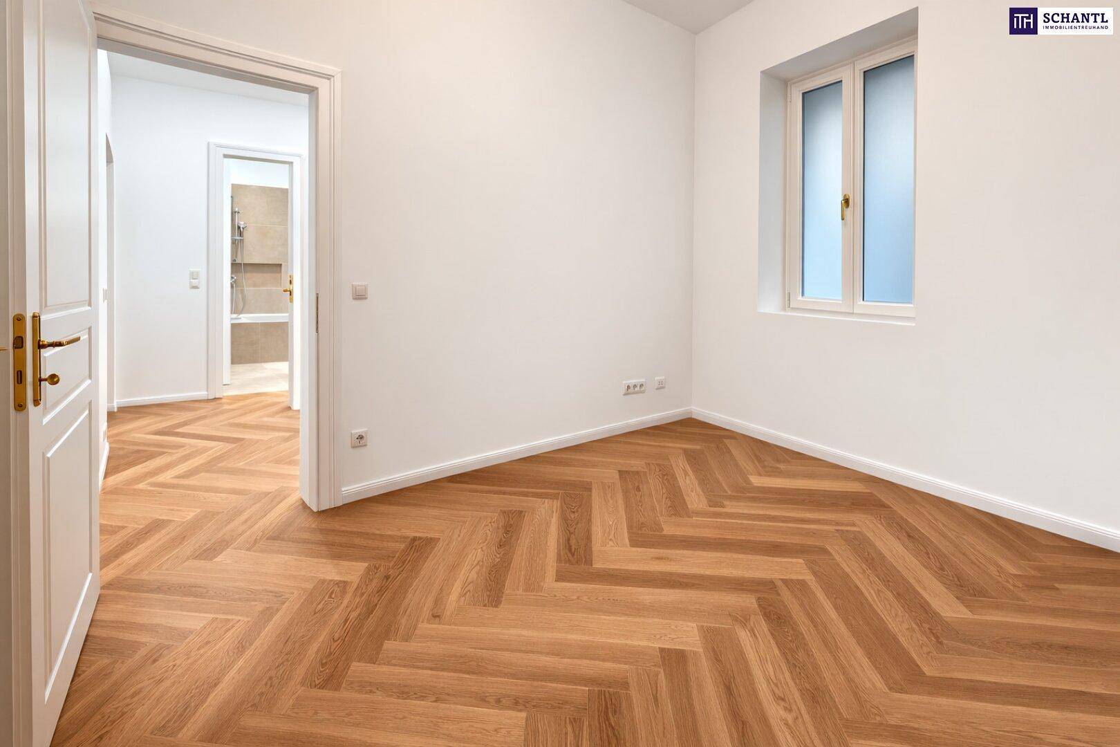 Unmöblierter Raum mit Fischgrätparkett und Zugang zu einem Badezimmer, ideal für ein Schlafzimmer.