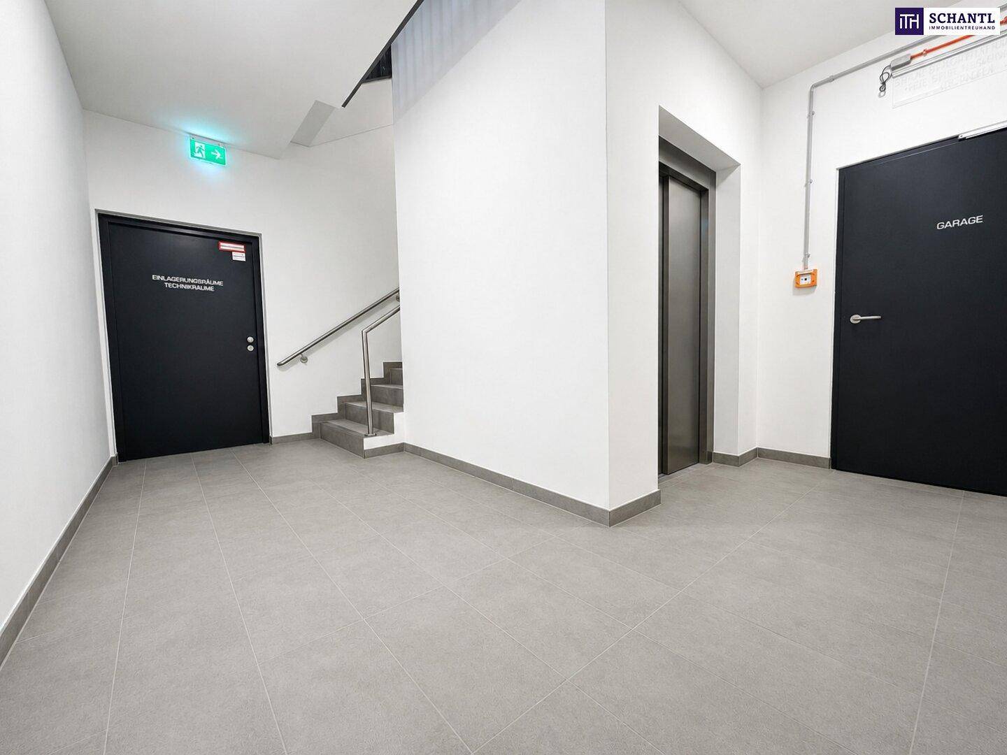 Moderner Flur mit Treppenhaus, Aufzug und Zugangstüren zu verschiedenen Bereichen des Gebäudes.