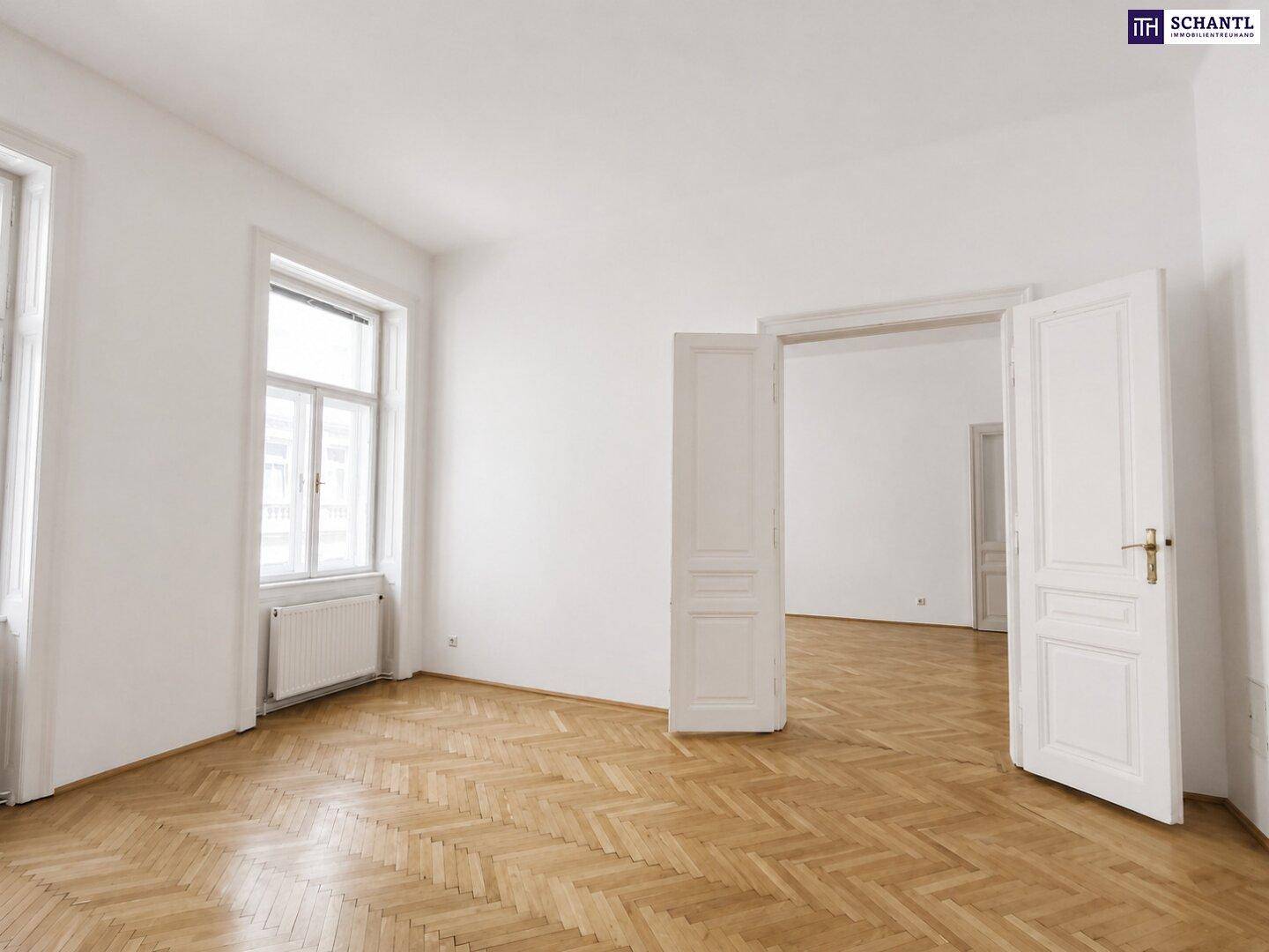 Geräumiges Zimmer mit klassischem Fischgrätparkett und hohen Doppeltüren zu einem angrenzenden Raum.