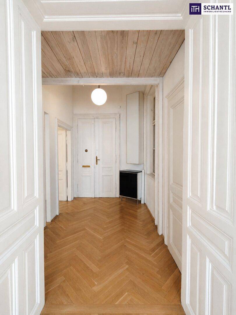 Langer Flur mit elegantem Fischgrätparkett, Holzdecke und klassischen Doppeltüren.