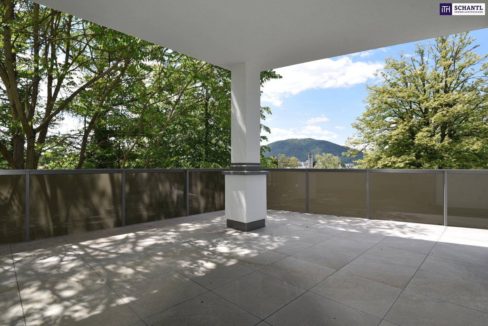 Überdachte Terrasse mit Fliesenboden und weitem Blick auf die grüne Landschaft und Berge.