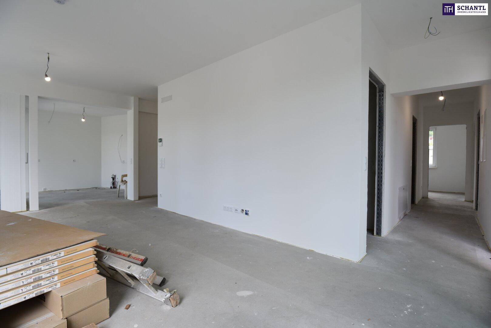 Geräumiger, unfertiger Innenraum mit weißen Wänden und Betonboden, bereit für den Ausbau.