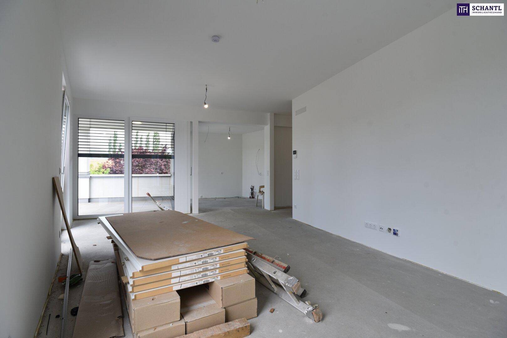 Großer, unfertiger Raum mit weißen Wänden und Betonboden, bereit für den Innenausbau.