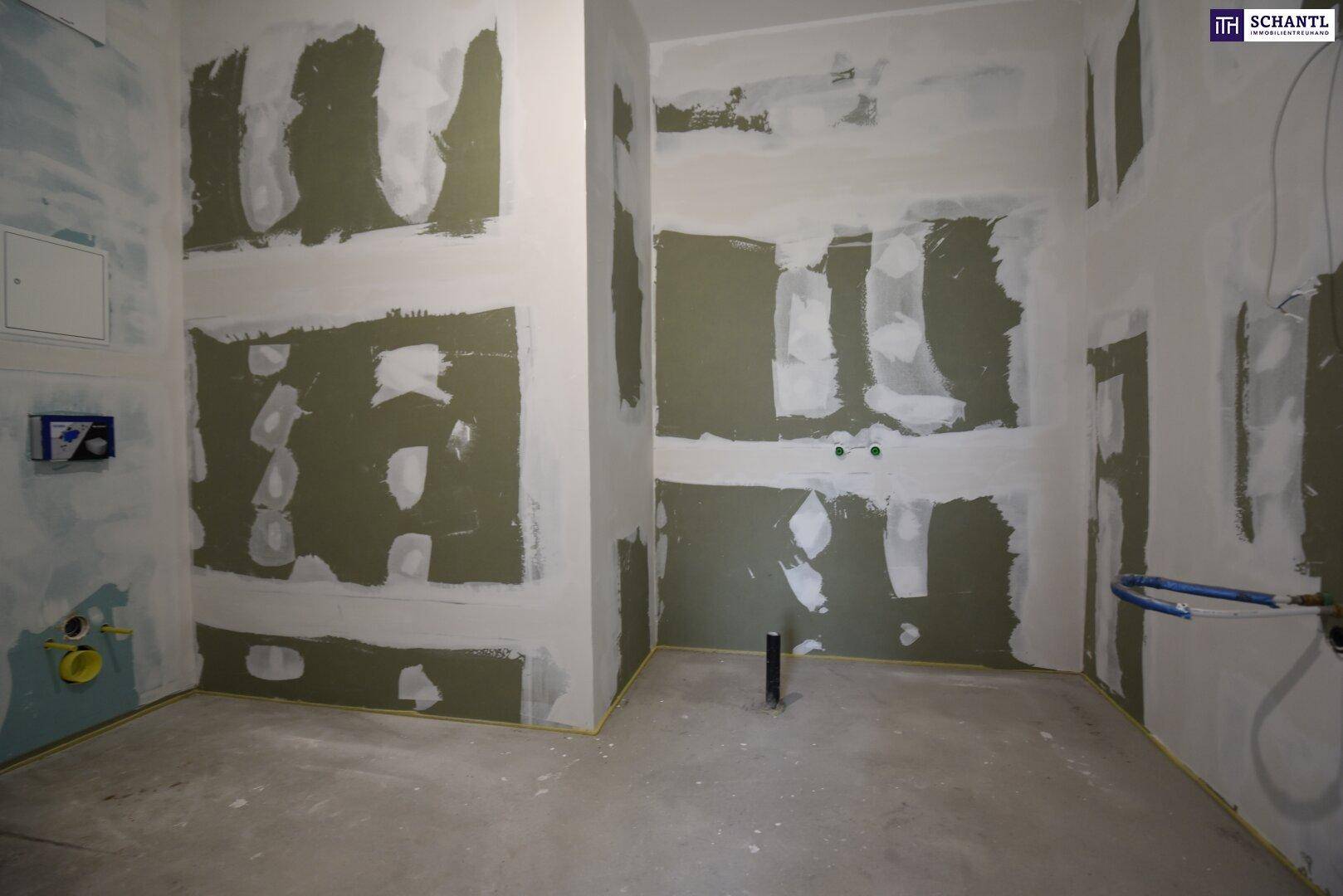 Unfertiges Badezimmer mit vorbereiteten Wänden und Sanitäranschlüssen für den Ausbau.