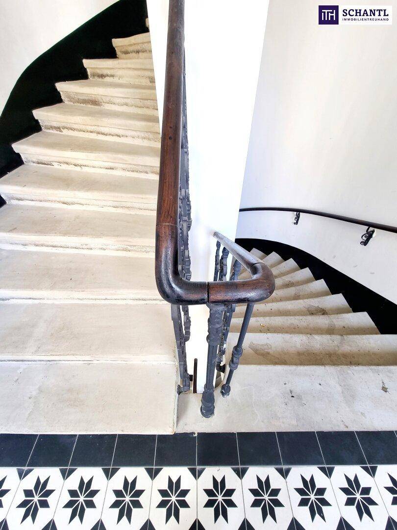Detailansicht eines eleganten Treppenhauses mit Holzhandlauf und kunstvollem Geländer.