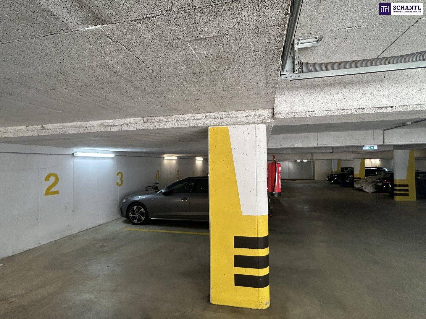 Geräumige Tiefgarage mit markierten Stellplätzen, einem geparkten Auto und einem Sicherheitspfeiler.