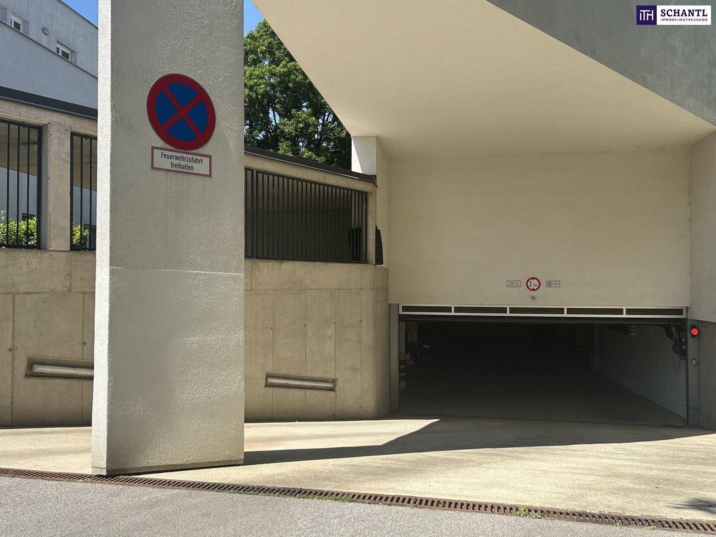 Eingangsbereich einer Tiefgarage mit Betonstruktur, Einfahrt und einem Halteverbotsschild.
