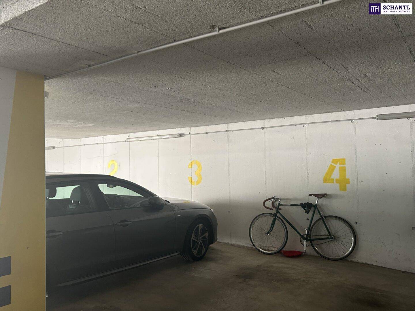 Tiefgaragenstellplatz mit einem geparkten Auto und einem Fahrrad an der Wand.